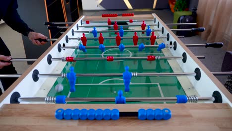 Video-displays-two-people---a-man-and-a-woman-enjoying-a-break-in-an-office-playing-table-soccer-knows-as-foosball