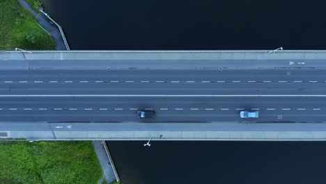 Cars-zoom-across-bridge-spanning-placid-calm-water-of-river