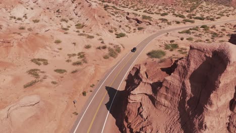 Cars-passing-on-the-road-between-the-rock-formations-of-the-Quebrada-de-las-Conchas,-Salta,-Argentina