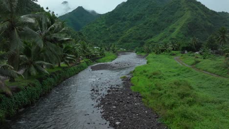 Teahupoo-Tahiti-French-Polynesia-aerial-drone-mountains-morning-grey-gray-raining-fog-season-wet-green-grass-end-of-the-road-Point-Faremahora-village-town-buildings-island-forward-pan-up