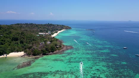 Aerial-view-of-phi-phi-island-with-turquoise-water,-boats,-luxury-resorts-and-mountainous-landscapes