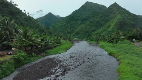 Teahupoo-River-Tahiti-French-Polynesia-aerial-drone-mountains-morning-grey-gray-raining-fog-season-wet-green-grass-end-of-the-road-Point-Faremahora-village-town-buildings-island-forward-pan-reveal