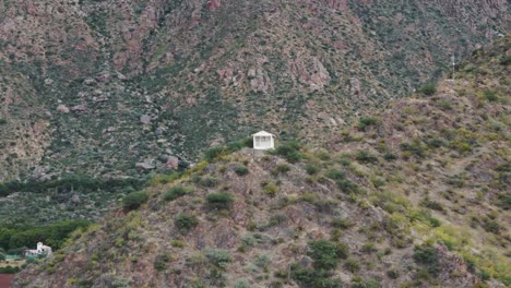 Drone-hovering-over-the-top-of-the-mountain-capturing-a-white-religious-house-situated-at-the-top