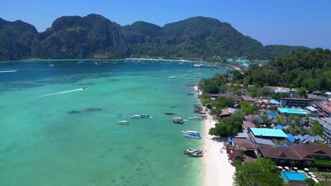 Aerial-view-of-phi-phi-island-with-turquoise-water,-boats,-luxury-resorts-and-mountainous-landscapes