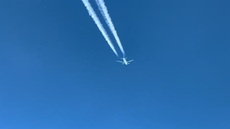 Pilot-POV-of-a-white-jet-crossing-left-to-right-across-a-blue-sky,-with-its-contrail-visible