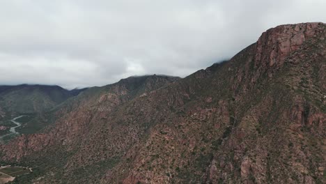 Drone-approaching-the-top-of-the-mountains-on-a-cloudy-day