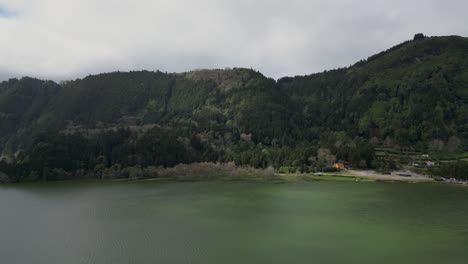 Aerial-view-of-mountains-with-dense-forests-close-to-a-green-lake