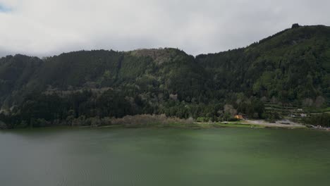 Vista-Aérea-De-Montañas-Con-Densos-Bosques-Cerca-De-Un-Lago-Verde