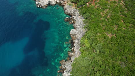 Das-Smaragdgrüne-Wasser-Des-Tiefen-Ionischen-Meeres-Spiegelt-Das-Grün-Der-Klippenhügel-Wider,-Bezaubernde-Texturen-Mit-Mediterranen-Farbtönen