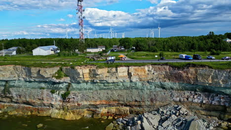 Aerial-of-Pakri-Cliff,-stone-edge-in-Estonia,-skyline-of-wind-farm,-green-energy