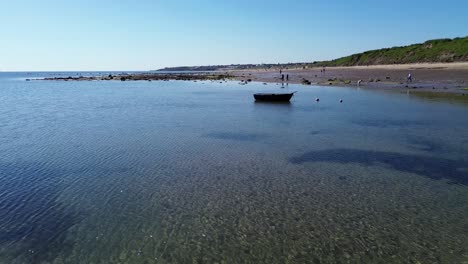 Rising-drone-shot-of-Whitley-Bay-Beach,-UK,-with-clear-waters-and-rowing-boat