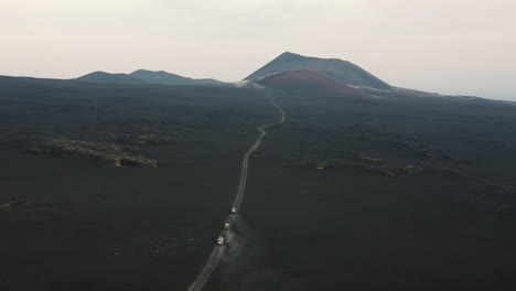 Aerial-view-of-three-off-road-vehicles-driving-around-volcanic-desert-landscape