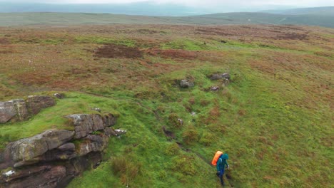 Static-aerial-view-of-tourist-walking-downhill-with-beautiful-landscape-at-background-in-England