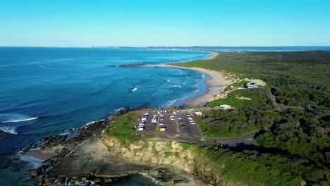 Landscape-scenic-view-of-vehicles-parked-in-carpark-on-cliff-headland-Norah-Head-Soldiers-beach-suburbs-bushland-ocean-waves-coastline-Central-Coast-Australia-tourism