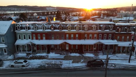 Colorful-row-of-townhouses-in-front-of-frozen-River-with-bridge-and-golden-sunset