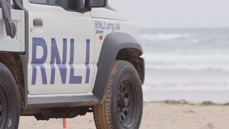 Telephoto-static-shot-of-RNLI-lifeguard-beach-patrol-truck-facing-the-ocean