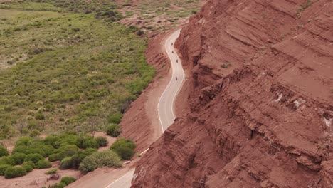 Drone-Capta-A-Un-Club-De-Motociclistas-Conduciendo-Por-La-Ruta-Del-Paso-Montañoso-En-Calchaquí-Salta,-Argentina