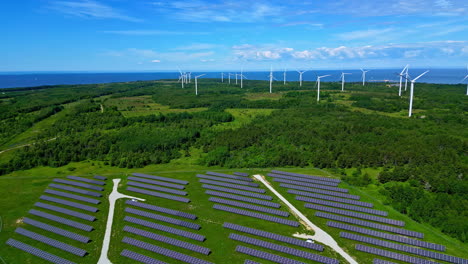 Aerial-drone-shot-over-solar-panels-with-windmills-in-the-background-in-Paldiski-Wind-Park,-Pakri-peninsula,-Estonia,-Europe