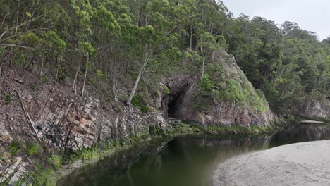 River-running-around-rocks-with-trees-and-sand-bank,-drone,aerial