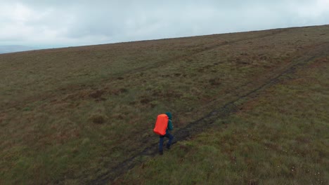 Aerial-pan-shot-of-passionate-backpacker-walking-towards-Five-Stones-on-a-cloudy-day-in-England