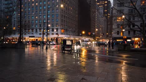 Shot-of-the-crossing-of-West-59th-Street-towards-6th-Avenue-from-the-sidewalk-of-Central-Park-during-a-rainy-afternoon-in-Manhattan,-New-York-City