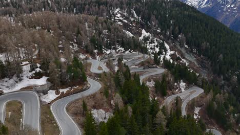 Aerial-View-captures-a-scenic-winding-mountain-road-amidst-a-forest-landscape,-with-patches-of-snow-visible,-providing-a-stunning-view-of-nature's-beauty-and-complexity-in-winter