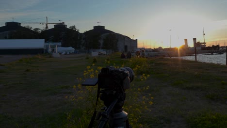 Video-displays-a-Canon-camera-EOS-R50-filming-a-sunset-in-Tallinn-harbor-with-people-enjoying-the-night-in-the-background-in-4K