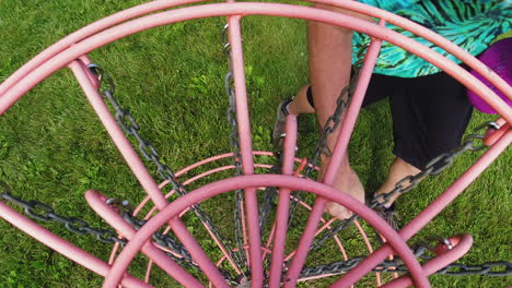 A-vibrant-pink-disc-lands-in-the-chains-of-a-disc-golf-basket,-capturing-the-dynamic-moment-of-a-successful-throw-in-a-grassy-park