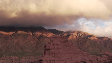 Aerial-view-of-the-pick-of-the-mountain-or-hills-at-sunset-in-Quebrada-de-las-Conchas,-majestic-scenery-with-thick-clouds-and-red-rock-formations