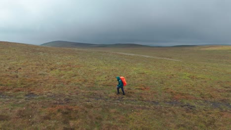 Aerial-side-view-of-tourist-carrying-orange-backpack-and-exploring-towards-Five-Stones-on-a-cloudy-day-in-EngLAND