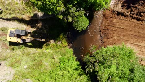 Luftaufnahme-Aus-Der-Vogelperspektive-Eines-Baggers,-Der-In-Der-Nähe-Eines-Flussbetts-Gräbt,-Umgeben-Von-üppigem-Grün-In-Chiloé,-Chile