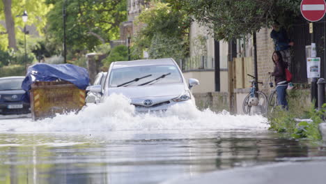 Los-Coches-Circulan-Por-La-Carretera-De-Londres-Fuertemente-Inundada-Con-Peatones-En-El-Pavimento