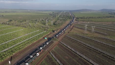 Aerial-orbit-of-a-massive-number-of-cargo-trucks-stuck-in-a-long-queue-on-a-highway-before-a-border-post