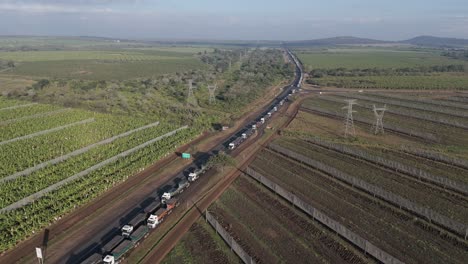 Luftaufnahme-Einer-Großen-Anzahl-Von-Lastwagen,-Die-In-Einer-Langen-Schlange-Auf-Einer-Autobahn-Vor-Einem-Grenzposten-Feststecken