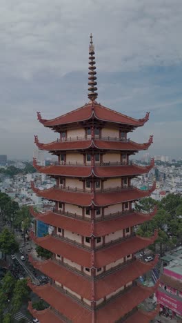 Vertical-video-of-Buddhist-Pagoda-in-Ho-Chi-Minh-City,-Vietnam-with-prayer-tower-and-red-roof-situated-in-densely-populated-area-of-the-city