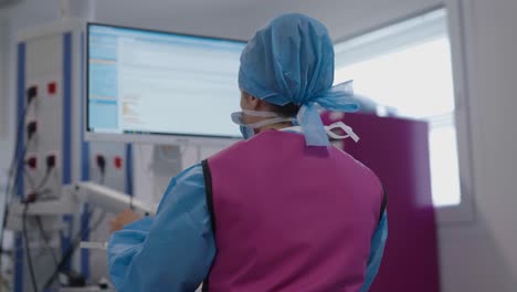 Rear-view-of-medical-nurse-working-on-computer-at-cardiology-department-of-French-hospital