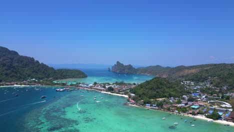 Aerial-view-of-phi-phi-island-with-turquoise-water,-boats,-luxury-resorts-and-mountainous-landscapes