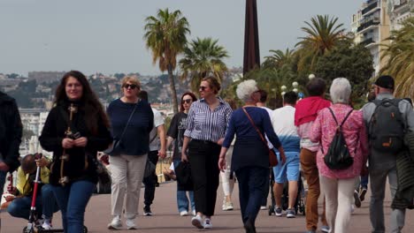 People-walk-along-bustling-Promenade-des-Anglais-in-Nice,-France-on-sunny-day