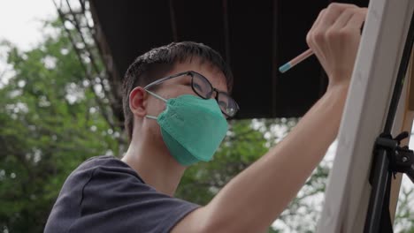 Niño-Asiático-Dibujando-Sobre-Lienzo-Con-Mascarilla,-Post-Covid,-Trauma-Pandémico