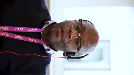 Confident,-bald-black-man-wearing-a-headset-and-lanyard,-participating-in-a-virtual-meeting-in-an-office-environment