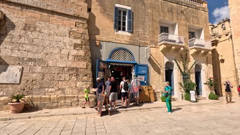 Capture-the-vibrant-scene-of-people-strolling-along-the-sunlit-streets-of-Mdina,-Malta,-embodying-the-essence-of-cultural-heritage-and-Mediterranean-ambiance