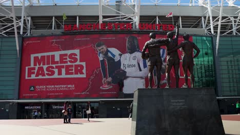 Manchester-United's-Old-Trafford-stadium-with-iconic-statues-and-promotional-billboard