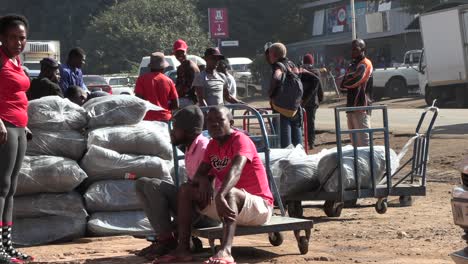 African-people-chat-and-relax,-seated,-while-others-stand-around-and-navigate-the-vibrant-sidewalk