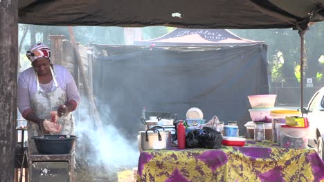 Eine-Afrikanische-Frau,-Die-Fleisch-In-Einen-Dampfenden-Topf-Schneidet-Und-Essen-Auf-Einem-Afrikanischen-Markt-Kocht