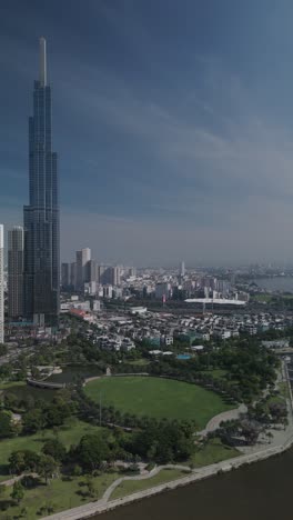 Vertical-video-of-Landmark-building-and-Central-park-along-the-Saigon-River-on-beautiful-sunny-day-with-blue-skies-showing-impressive-architecture-and-landscaping