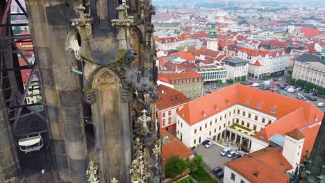 Vista-Aérea-Por-Drones-De-Una-Torre-De-Iglesia-Gótica-En-Brno,-República-Checa,-Con-Intrincados-Detalles-Arquitectónicos-Y-El-Paisaje-Urbano-Al-Fondo