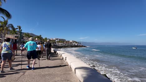 Tourists-walking-along-the-boardwalk-and-beachfront-In-Puerto-Vallarta,-Mexico