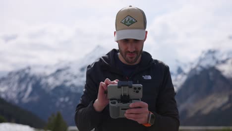 A-drone-pilot-holds-a-quadcopter-controller-with-smartphone-screen-in-hands-in-Swiss-alps