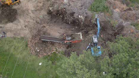 Flight-with-overhead-view-and-turns-with-the-camera-of-the-work-of-a-plant-material-crusher-supported-in-its-work-by-two-machines,-we-see-how-it-crushes-and-leaves-the-material-on-a-conveyor-belt