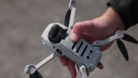 Hand-holds-a-drone,-presses-button-on-battery-to-turn-the-quadcopter-on